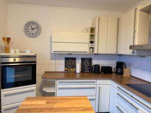 a kitchen with white cabinets and a clock on the wall at Deck in Cuxhaven +4 photos