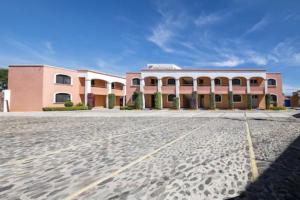 a pink and white building with a large courtyard at OYO Hotel La Glorieta, Huichapan in Huichapan