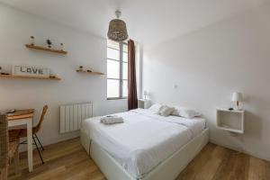 a white bedroom with a bed and a desk at Nid Amour Cabane et Spa Privatif in Rouen +3 photos