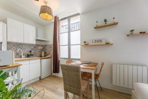 a kitchen with white cabinets and a table with chairs at Nid Amour Cabane et Spa Privatif in Rouen