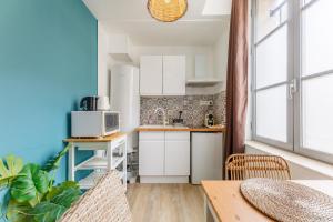 a small kitchen with white cabinets and a table at Nid Amour Cabane et Spa Privatif in Rouen