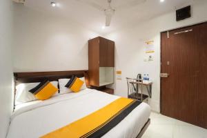 a bedroom with a bed with yellow and black pillows at Glitz Rexton Inn - Near IIT Powai in Mumbai +6 photos