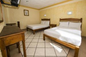 a bedroom with two beds and a table and a desk at OYO Hotel La Glorieta, Huichapan in Huichapan +17 photos
