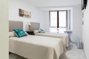two beds in a room with white walls and a window at Amarantos in Suances +57 photos