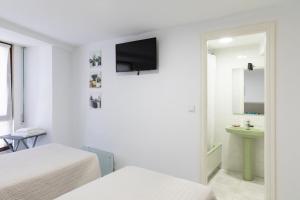 a bedroom with two beds and a television on the wall at Amarantos in Suances