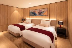 two beds in a room with wood paneling at The Auberg Collection Hotel in Ho Chi Minh City