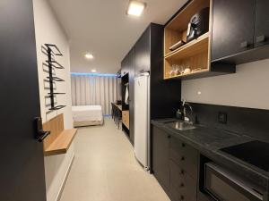 a kitchen with black cabinets and a bed in a room at Flat Praia Ponta de Campina in Cabedelo
