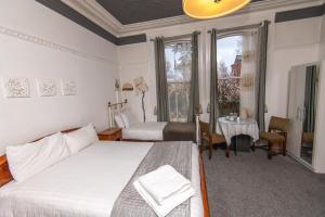 a bedroom with two beds and a table and a window at Cornerstone Manor Hotel in Sale