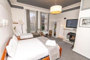 a bedroom with a bed and a tv and a fireplace at Cornerstone Manor Hotel in Sale