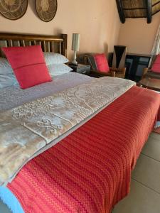 a bedroom with a bed with a red blanket on it at Lalakamnandi Guesthouse in Pretoria +7 photos