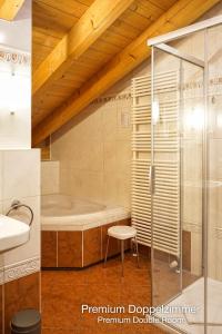 a bathroom with a tub and a glass shower at Landhotel Guglhupf in Schwangau +44 photos