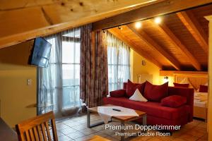 a living room with a red couch and a bedroom at Landhotel Guglhupf in Schwangau