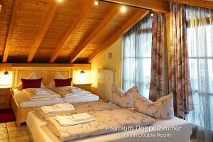 a bedroom with two beds and a large window at Landhotel Guglhupf in Schwangau