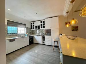 a kitchen with white cabinets and a wooden table at Imaani Homes - 2A at JAK Royale in Apenkwa