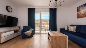 a living room with a blue couch and a table at Flatbook Rodzinne Apartamenty Jantar Resort z Parkingiem, Placem Zabaw i Wiatą Grillową in Jantar +24 photos