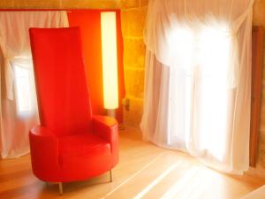 a red chair sitting in front of a window at Cas Ferrer Nou Hotelet in Alcudia