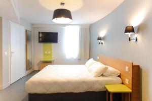 a bedroom with a bed and a tv on the wall at Hotel Reseda in Bagnolet