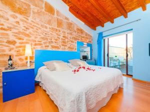 a blue bedroom with a bed and a stone wall at Cas Ferrer Nou Hotelet in Alcudia