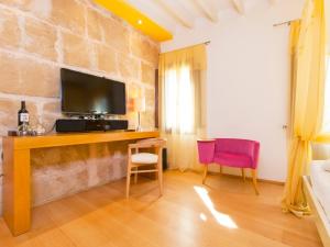 a living room with a tv on a stone wall at Cas Ferrer Nou Hotelet in Alcudia