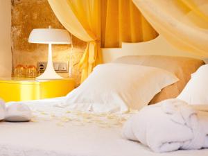 a bedroom with a bed with white sheets and a lamp at Cas Ferrer Nou Hotelet in Alcudia