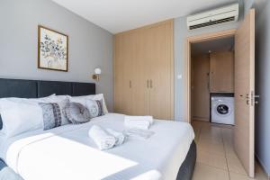 a bedroom with a large white bed with towels on it at 1BR Apt. next to Coralli Beach Protaras in Paralimni