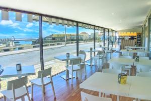 ein Restaurant mit Tischen und Stühlen und Meerblick in der Unterkunft Hotel Nobu Peniche in Peniche