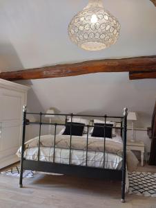 a bedroom with a bed and a chandelier at Le petit Moulin de Drée in Drée