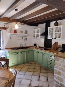 a kitchen with green cabinets and a sink and a table at Le petit Moulin de Drée in Drée