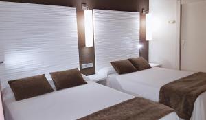 a hotel room with two beds and two lamps at Augustus in Cambrils