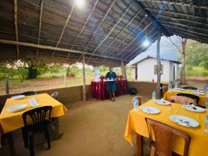 a man standing in front of a table with yellow tables at Villu Trails Wilpattu in Wilpattu