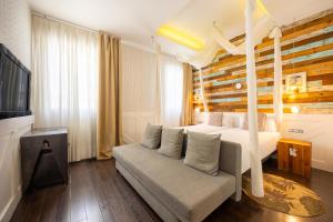 a bedroom with a bed and a couch and a television at Abalú Collection Hotel Life Gran Via in Madrid