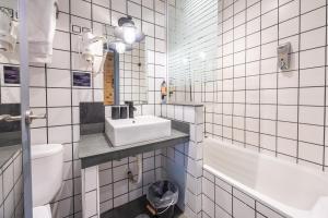 a white tiled bathroom with a sink and a toilet at Abalú Collection Hotel Life Gran Via in Madrid +53 photos