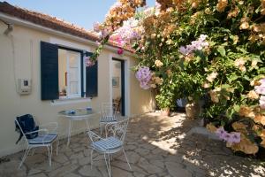 a patio with a table and chairs and flowers at Eleni's Cottage in Fiskardo