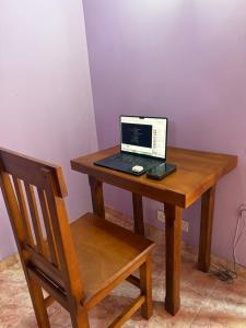a laptop computer sitting on a wooden desk with a chair at The Layover Hostel in Katunayaka
