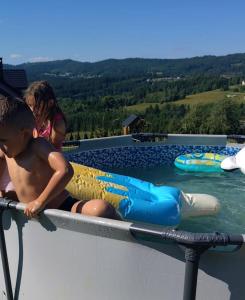 a young boy sitting on a raft in a swimming pool at Wśród Gór in Istebna