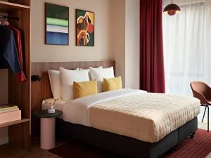 a bedroom with a large bed and a red curtain at Numa Rotterdam Coolsingel in Rotterdam