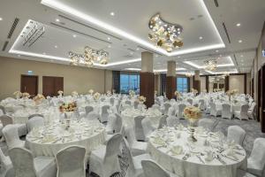 a banquet hall with white tables and chairs and chandeliers at Doubletree By Hilton Afyonkarahisar in Afyon +49 photos