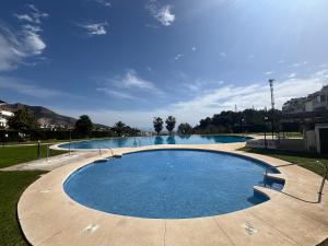 a large swimming pool with blue water in a park at Apartamento Benalmarina in Benalmádena +12 photos