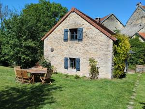 a table and chairs in front of a stone house at Le petit Moulin de Drée in Drée
