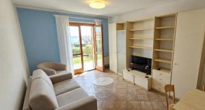 a living room with a couch and a tv at Appartamenti Vista Lago - Costermano sul Garda - Be Happy! in Costermano sul garda