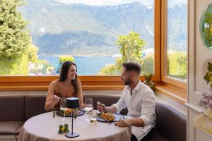 a man and woman sitting at a table in a restaurant at Hotel Du Lac in Limone sul Garda