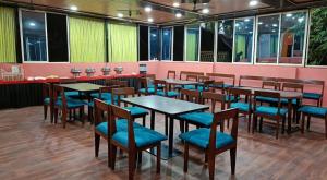 a restaurant with wooden tables and blue chairs at Royal Resort in Indore