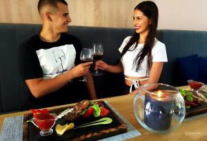 a man and a woman sitting at a table with wine glasses at Glory Apart Polyana in Polyana