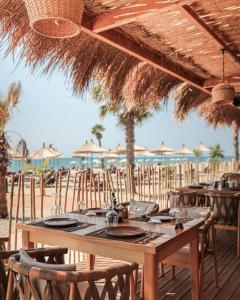 a wooden table with chairs and umbrellas on the beach at Albatros Beach & Resort in Rrogozhinë