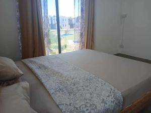 a bed in a bedroom with a large window at Duplex Green Village in Grande Gaube