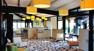 a lobby of a restaurant with yellow lights and chairs at Relais Fasthotel Port Lauragais in Avignonet-de-Lauragais