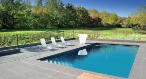 a swimming pool with four chairs next to at Relais Fasthotel Port Lauragais in Avignonet-de-Lauragais