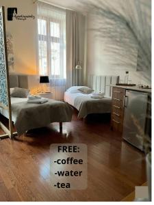 a room with two beds and a sign for free coffee water tea at Apartamenty Przemyśl in Przemyśl