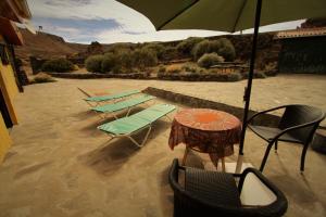 a table and chairs with an umbrella in the sand at Casa Tajinastes del Teide in Las Cañadas del Teide