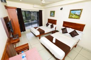 a hotel room with two beds and a television at Velan Temple View in Palni